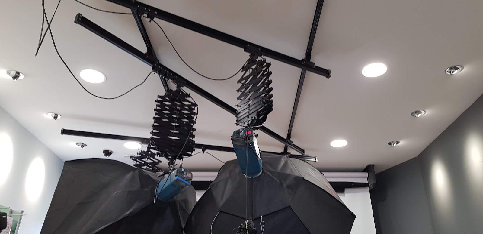 Studio ceiling with track-mounted rail system, softbox modifiers on pantograph arms and recessed downlights