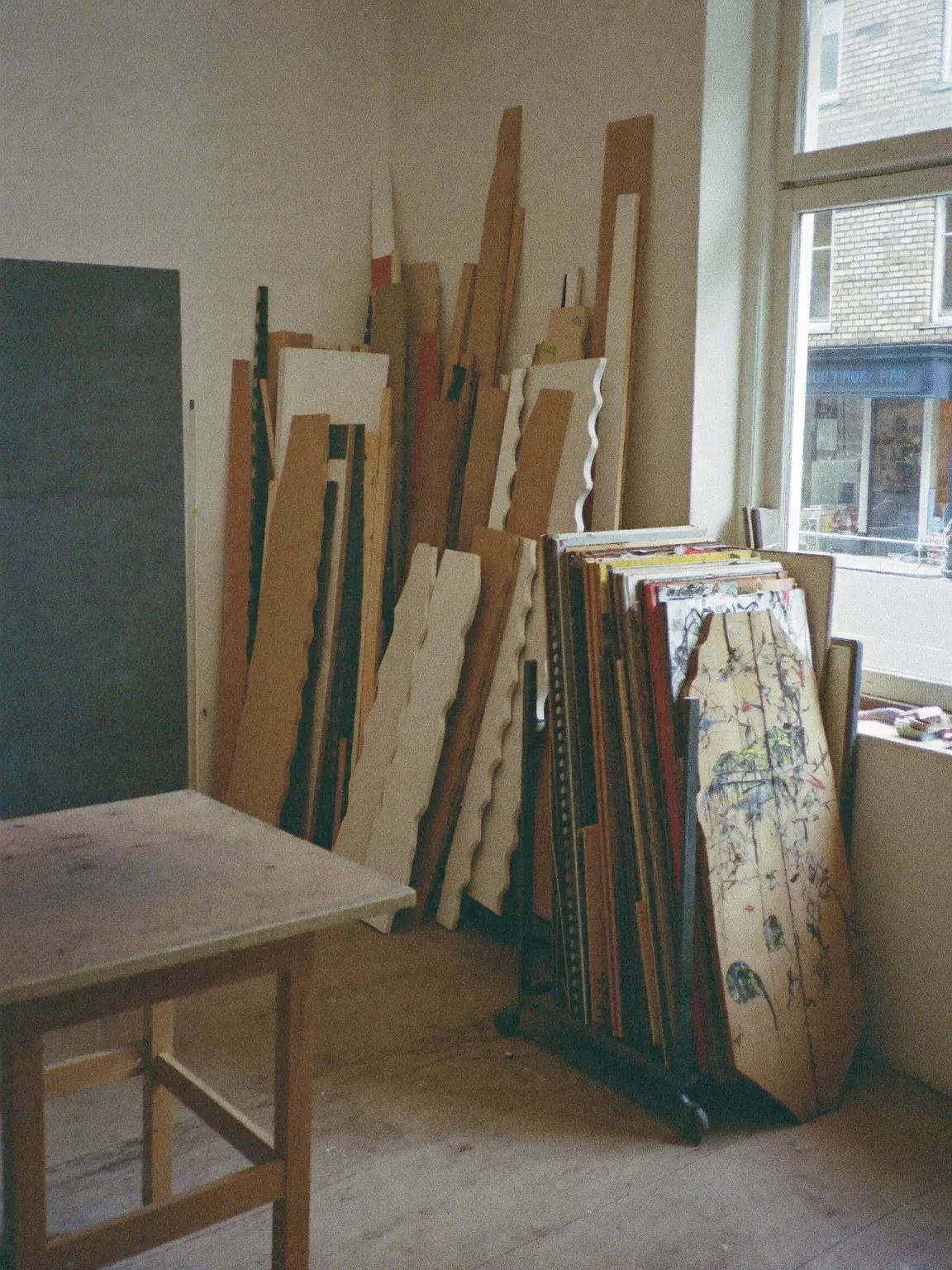 Corner of the framing workroom with moulding lengths racked upright and cut mount board on the bench